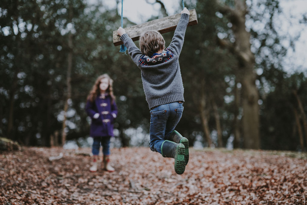 Children playing in a forest on a swing
